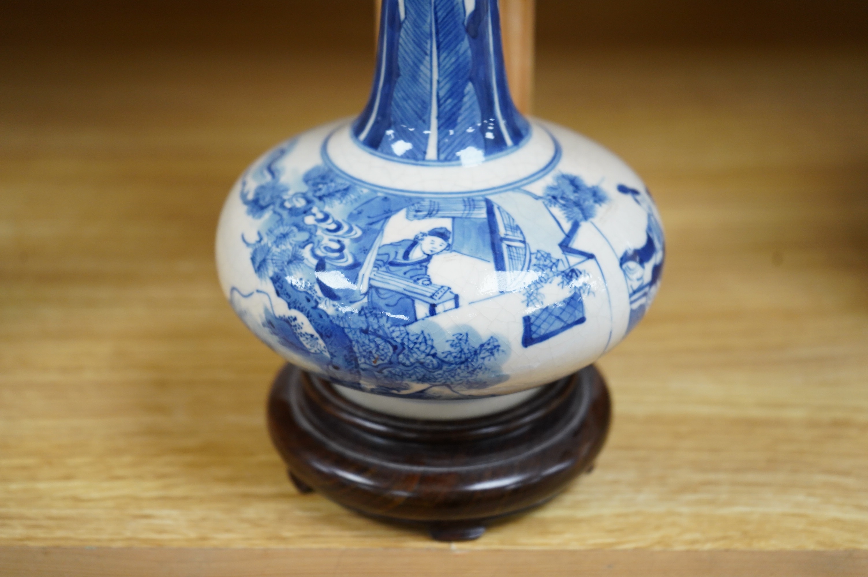 A 19th century Chinese blue and white crackle glaze bottle vase on hardwood stand, 20cm total. Condition - firing cracks to neck interior